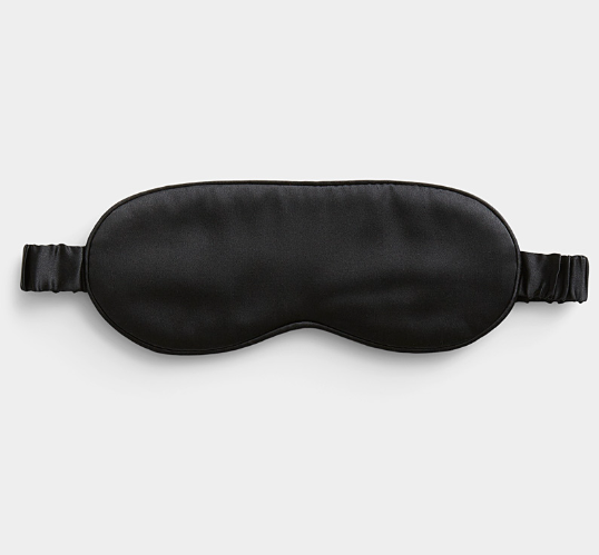 Black satin sleep mask on a light gray background