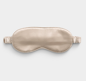 Beige satin sleep mask on a light gray background