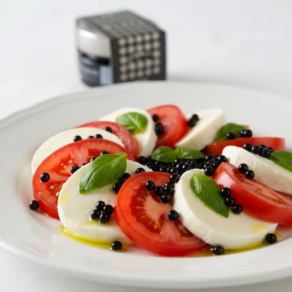 Caprese salad with tomatoes, mozzarella, basil, and black olives on a white plate.
