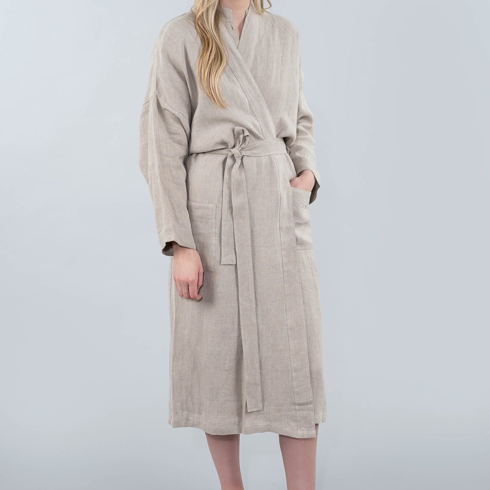 Woman wearing a beige robe against a plain background