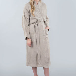 Woman wearing a beige robe against a plain background