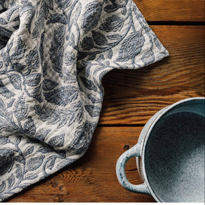 Floral patterned fabric on a wooden surface with a blue ceramic cup.