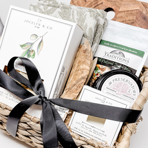 Gift basket with black ribbon, including a book and various items, on a white background.