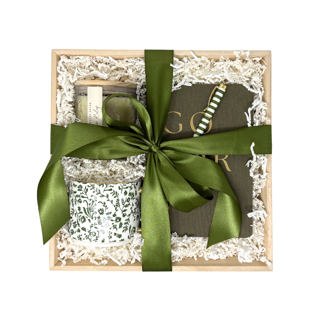 Gift set with candles and a book tied with a green ribbon on a white background