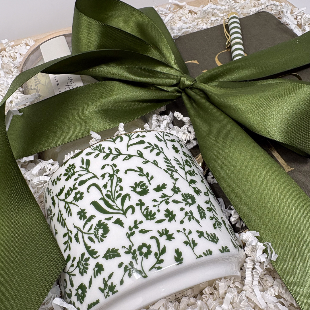 Gift set with candles and a book tied with a green ribbon on a white background