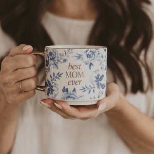 Person holding a mug with 'best MOM ever' text and floral design