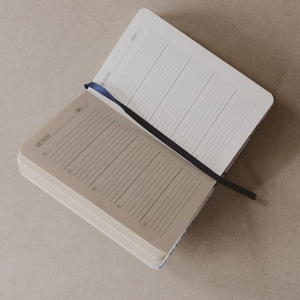 Two notebooks stacked on a beige surface