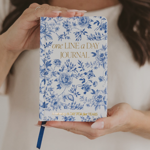 One Line a Day Journal with blue floral design held by hands against a neutral background