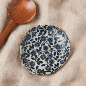 Ceramic plate with blue floral pattern next to a wooden spoon on a beige fabric background