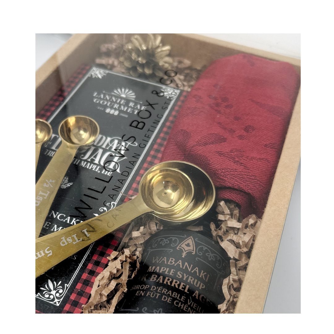 Pancake mix, dishcloth, maple syruo and gold measuring spoons.