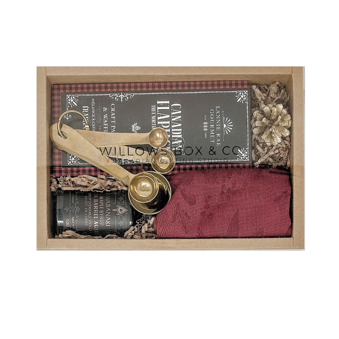 Pancake mix, dishcloth, maple syruo and gold measuring spoons.