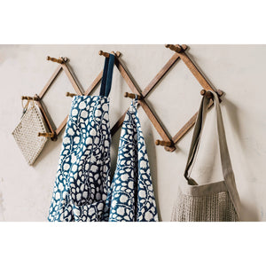 Wooden wall hook with aprons hanging on a light-colored wall