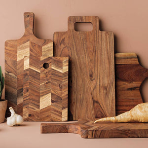 Set of wooden cutting boards on a beige surface with plants and garlic.