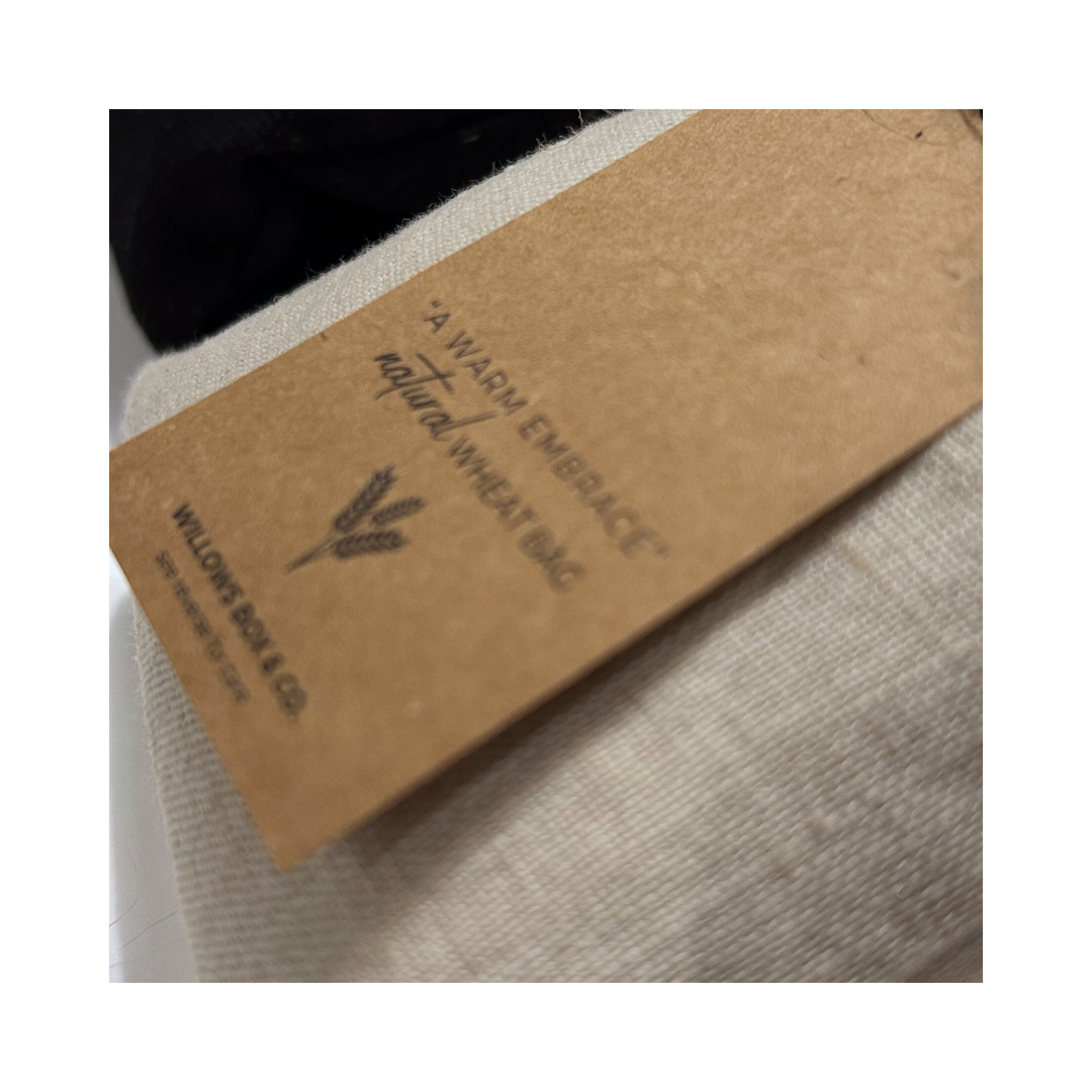 Three linen hot/cold therapy bags in pink, white, and black colors, stacked on top of each other.