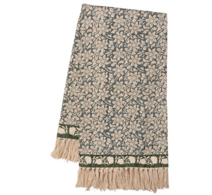 A rectangular woven throw blanket featuring an all-over floral pattern in beige and muted blue-gray, finished with a decorative border and cream fringe tassels.