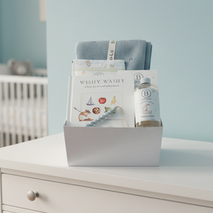 Baby gift set with book, blanket, and bottle in a box on a white background