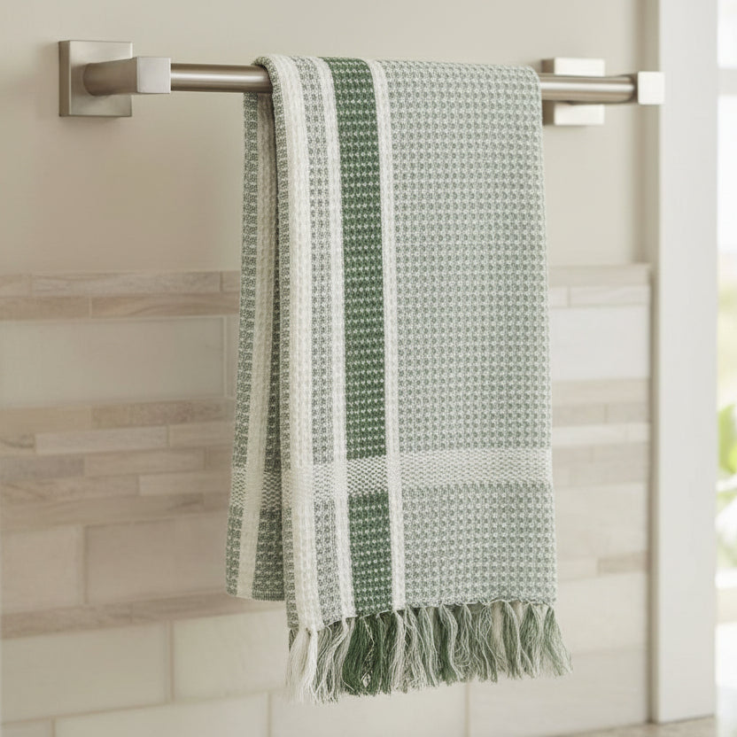 Green and white patterned towel with fringes on a white background