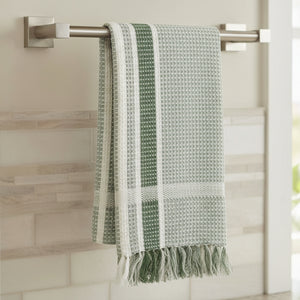 Green and white patterned towel with fringes on a white background