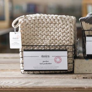 Three woven bags with tags on a wooden surface, blurred background