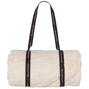 Rolled-up throw blanket with a black strap featuring 'Lana Grossa' branding on a white background