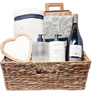 Gift basket with towels, bottles, and a bottle of wine on a white background