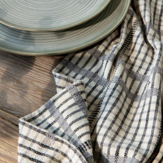 Stack of light green ceramic plates on a wooden surface with a checkered cloth.