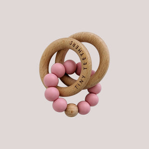 Pink teething ring with wooden elements on a white background