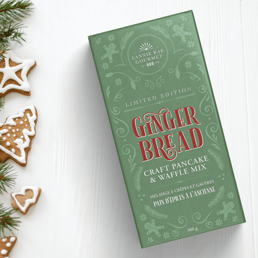 Green box of gingerbread craft pan cake & waffle mix with Christmas cookies on a white background