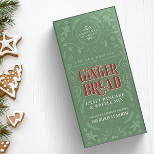 Green box of gingerbread craft pan cake & waffle mix with Christmas cookies on a white background