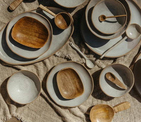 Three nested wooden measuring cups with long handles, shown on a plain off-white background.