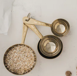 Set of brass measuring cups and spoons on a light surface
