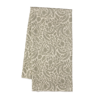 A folded rectangular textile, likely a towel or blanket, featuring an all-over floral damask pattern in warm taupe and beige tones, shown against a plain white background.