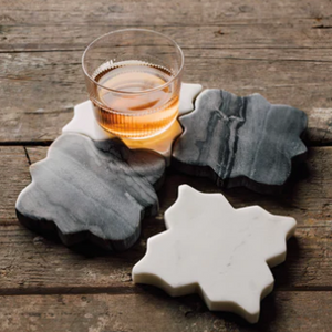 Glass of amber liquid on a set of stone coasters on a wooden surface