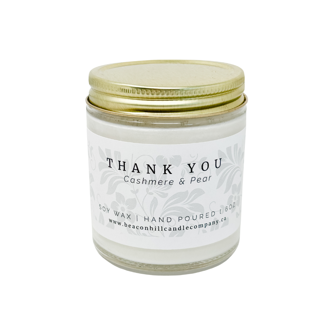 Candle jar with a gold lid and 'Thank You' label on a white background