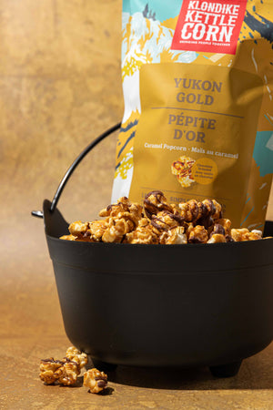 Kettle corn in a black bucket with a Klondike Kettle Corn bag in the background.