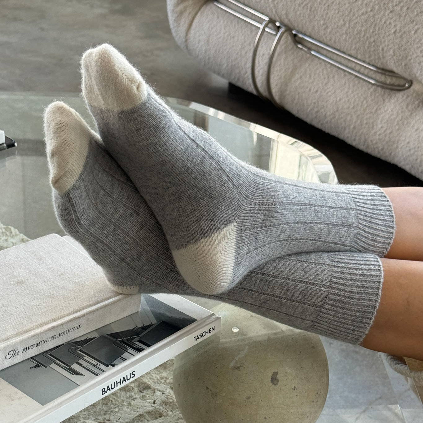 Pair of gray socks with white toes and cuffs on a light gray background