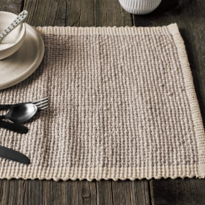 A rectangular woven placemat in a natural beige jute or seagrass material, featuring a solid beige border with scalloped edges, shown against a plain white background.